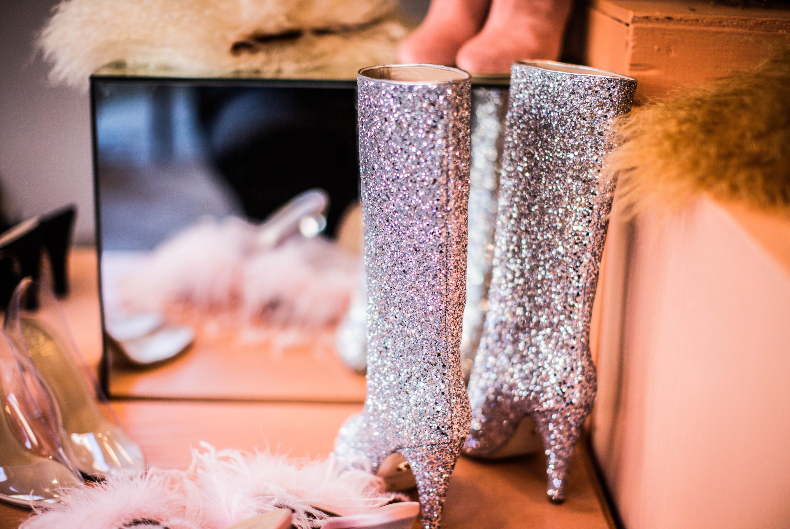 photograph of silver glitter heeled boots, a mirror and accessories strewn across a dressing room